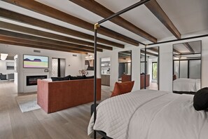 Un dormitorio moderno con una cama grande, una zona de estar con sofá y un armario con espejo.