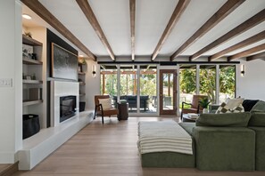 Uma sala de estar ampla com lareira, assentos e grandes janelas.
