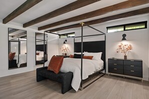 Quarto moderno com cama de dossel, mesa de cabeceira, cômoda e espelho grande.