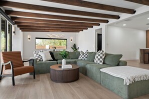 Uma sala de estar moderna com sofá modular, mesa de centro redonda e uma cadeira de madeira.