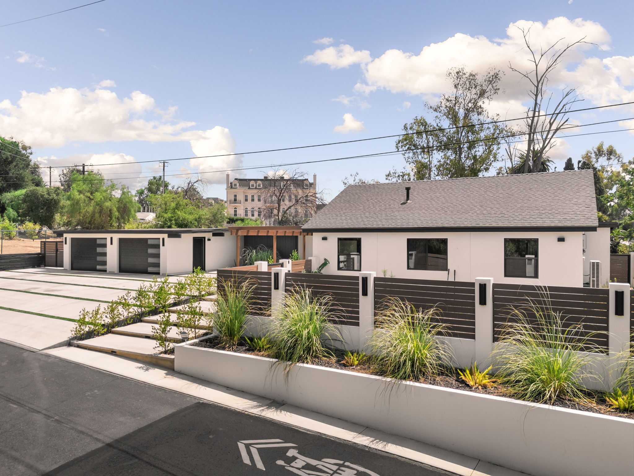 A modern two-story building with a flat roof, large windows, and a gated entrance.