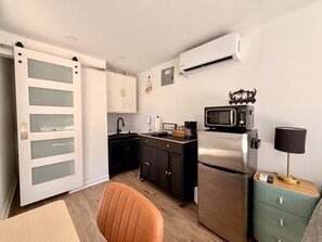 Eine kleine Küche mit Kühlschrank, Mikrowelle und Kaffeemaschine.