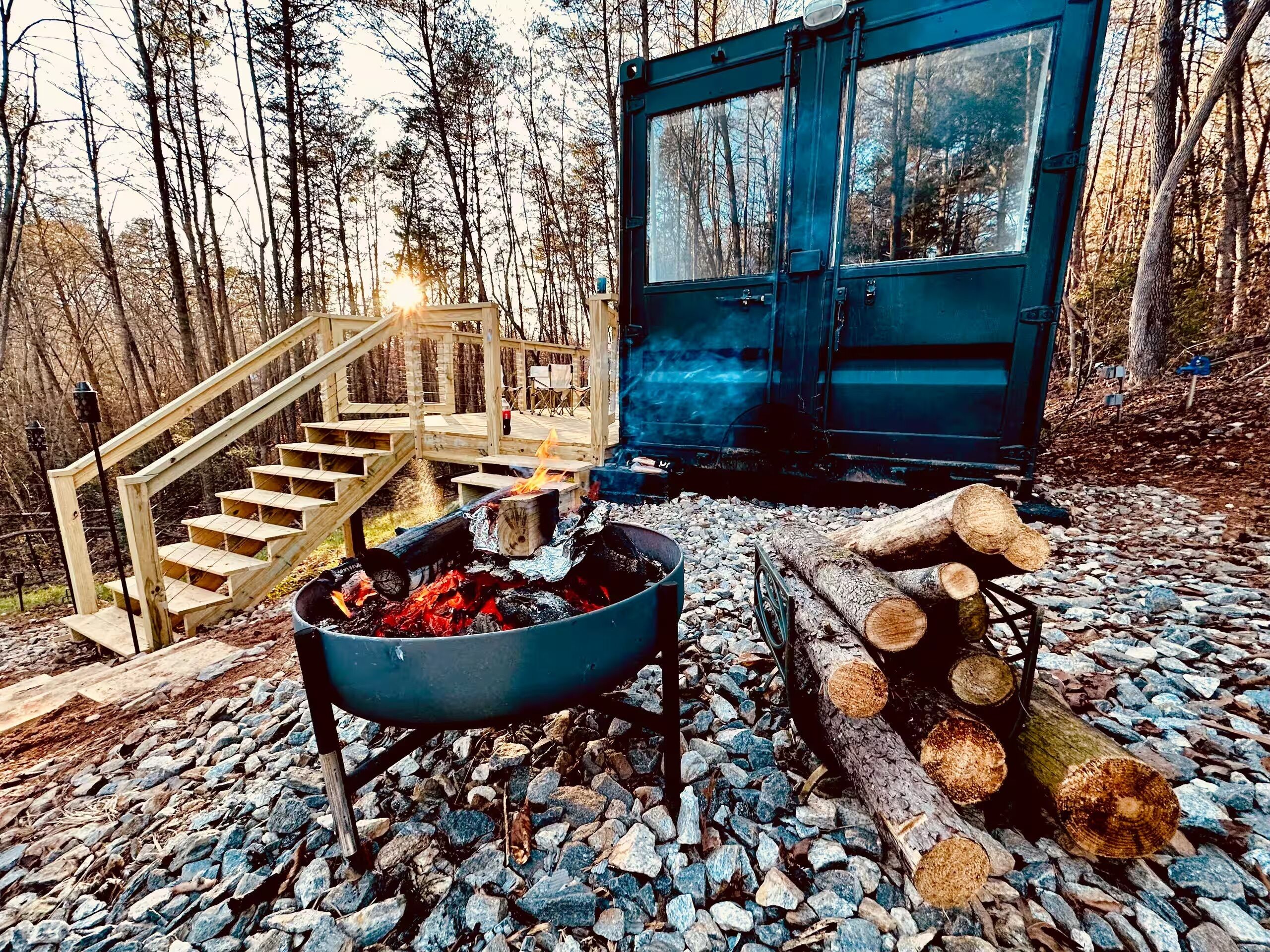 A rustic outdoor setting with a fire pit, a wooden staircase, and a cabin.
