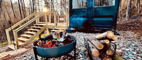 A rustic outdoor setting with a fire pit, a wooden staircase, and a cabin.