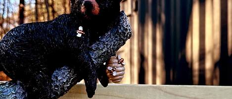 Una escultura de oso sobre un banco de madera al aire libre.