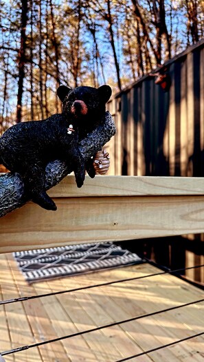 A bear sculpture on a wooden bench outdoors.