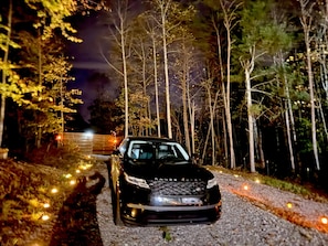 A car parked on a gravel path surrounded by trees at night.