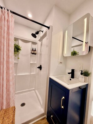 Ein modernes Badezimmer mit Dusche, Waschbecken mit Spiegel und Ablage.