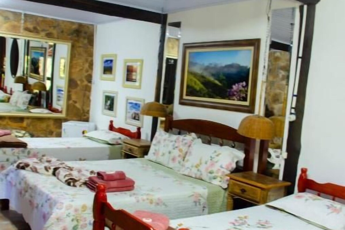 Habitació d'hotel amb dos llits, un capçal de llit de fusta, una tauleta de nit, un mirall i un quadre amb marc a la paret.