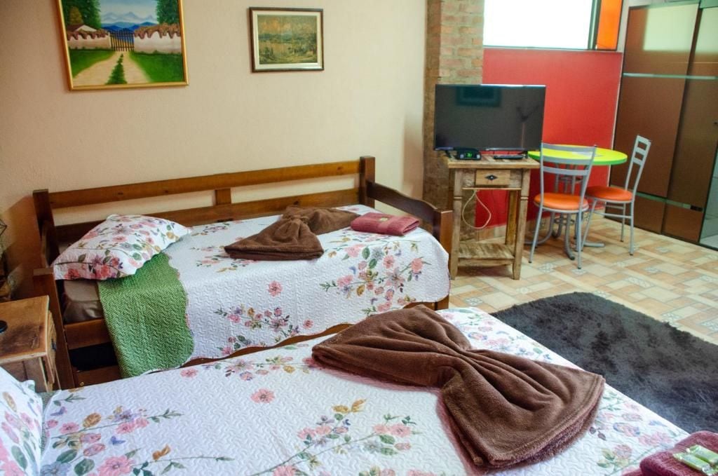 Ein Schlafzimmer mit einem Bett, einem Schreibtisch, einem Sessel und einem Fernseher.