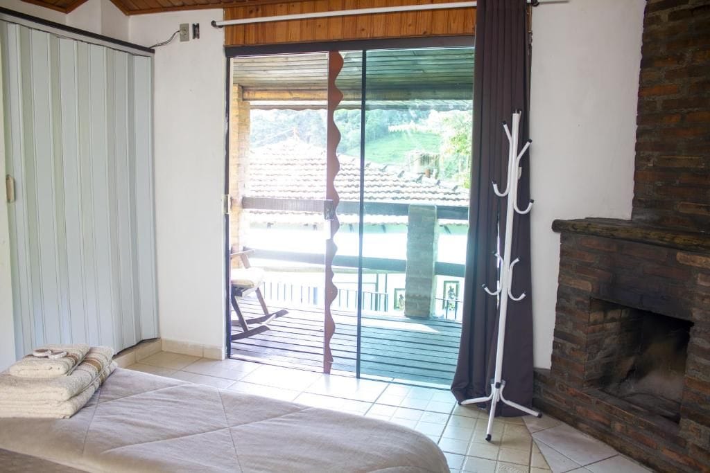 Una habitación con cama, chimenea, balcón con vistas y perchero.