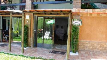 A hotel entrance with a glass door, a sign indicating 'Arauçaria,' and a small garden area with a bench and potted plants.