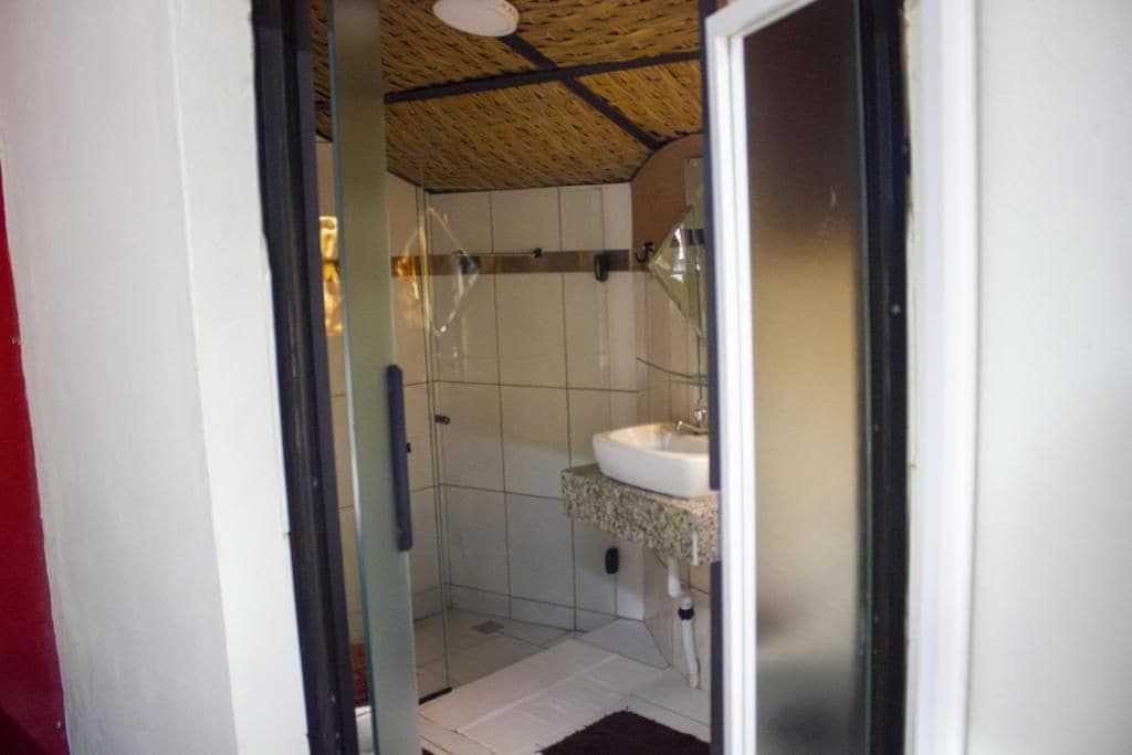 Een badkamer met een douchecabine van glas, een wit wastafelmeubel en een betegelde vloer.
