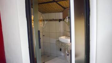 Een badkamer met een douchecabine van glas, een wit wastafelmeubel en een betegelde vloer.