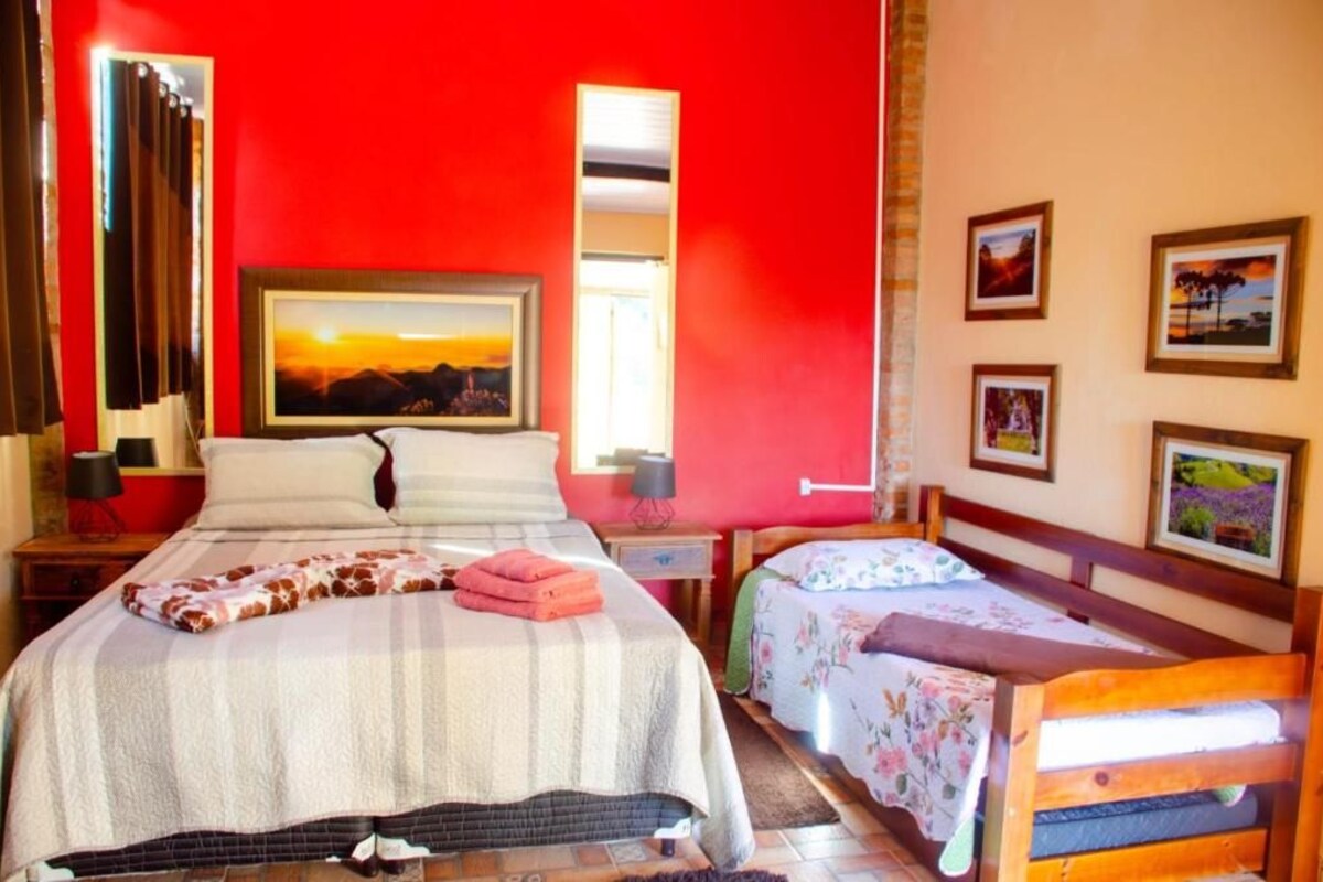 Una habitació d'hotel amb un llit gran, un altre més petit, un quadre a la paret i una finestra.