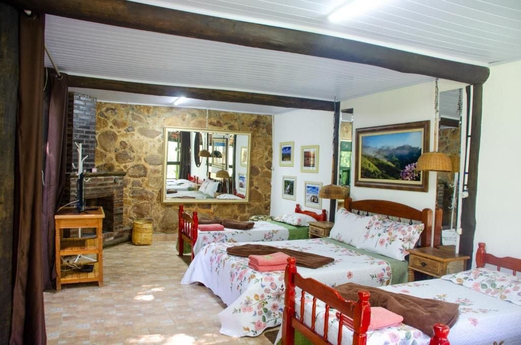 A room with two beds, a stone wall, a fireplace, and a mirror.
