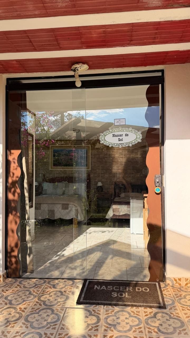 A hotel entrance with a glass door, a doormat, and a sign reading 'Naser do Sol'.