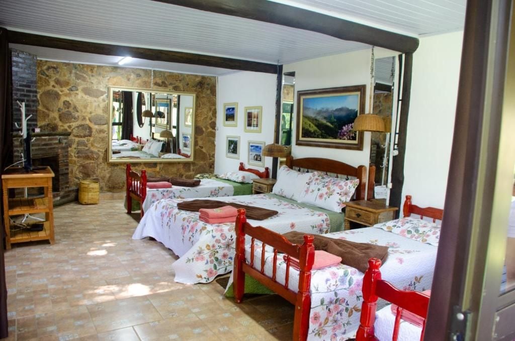 Quarto com duas camas, uma parede de pedra, um espelho e um quadro.