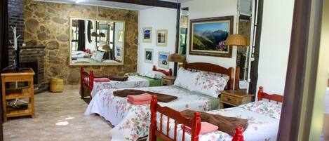Quarto com duas camas, uma parede de pedra, um espelho e um quadro.