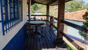 A covered outdoor area with a table and chairs, a view of a river, and a blue fence. - Pousada Estância Vip (Cunha)