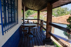 Zona exterior coberta amb una taula i cadires, vista d'un riu i una tanca blava.