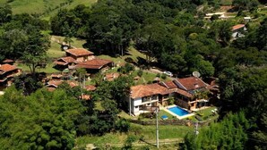 A residential area with multiple houses, a swimming pool, and lush greenery. - Pousada Estância Vip (Cunha)