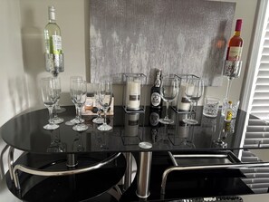 A bar area with a round table, glasses, bottles, and a decorative wall. - 2-bedroom bed & breakfast in nice Syracuse with front fenced in yard (Syracuse)