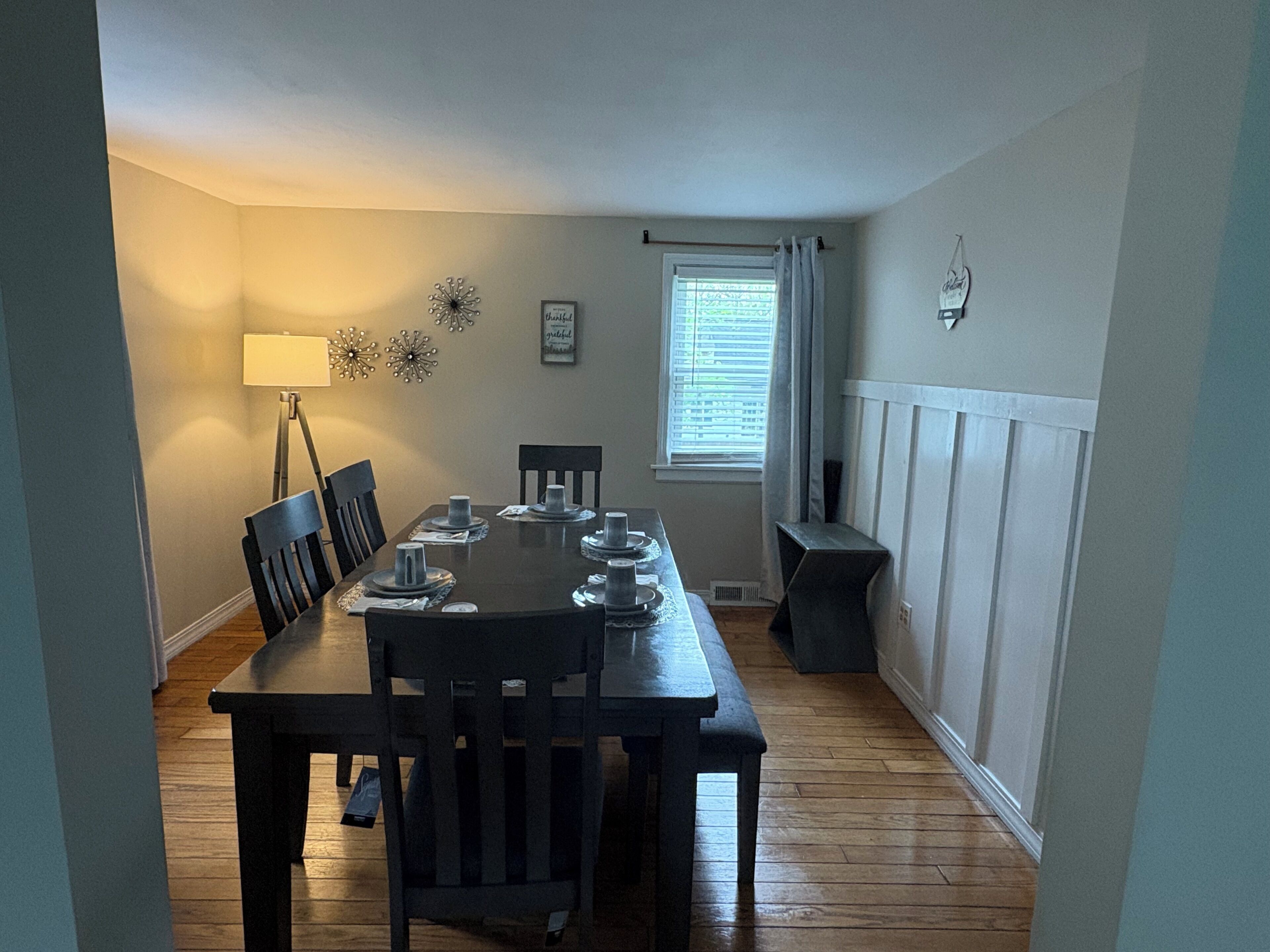Une salle à manger avec une table rectangulaire dressée pour quatre personnes, et deux chaises de chaque côté.