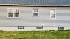 A single-story house with a grey roof and white siding, featuring three windows and a small front porch. - 2-bedroom bed & breakfast in nice Syracuse with front fenced in yard (Syracuse)