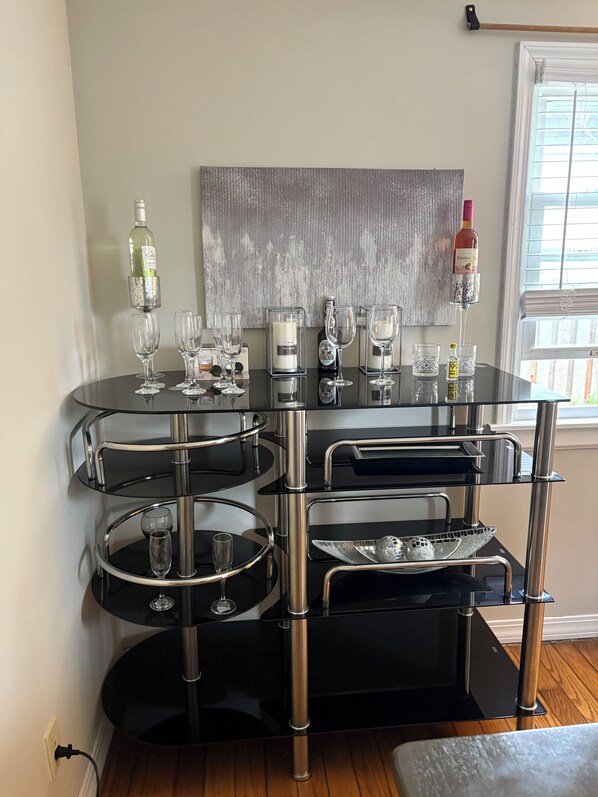 A modern, multi-tiered black bar with glass shelves, wine bottles, and glasses.