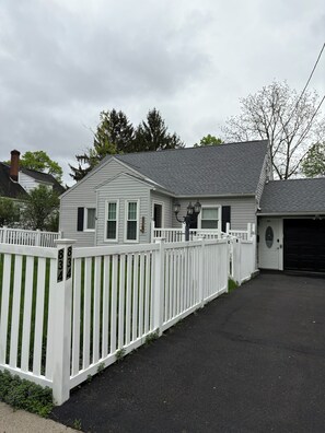 A residential property with a white picket fence, a garage, and a driveway. - 2-bedroom bed & breakfast in nice Syracuse with front fenced in yard (Syracuse)