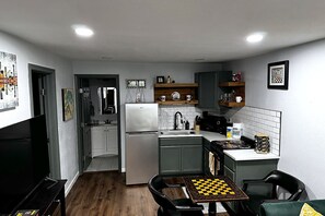 A compact kitchen with a refrigerator, sink, and a chessboard on the dining table. - Cozy Bungalow-Dallas Central (Dallas)