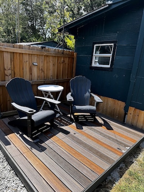 An outdoor deck with two Adirondack chairs and a small round table. - Cozy Bungalow-Dallas Central (Dallas)