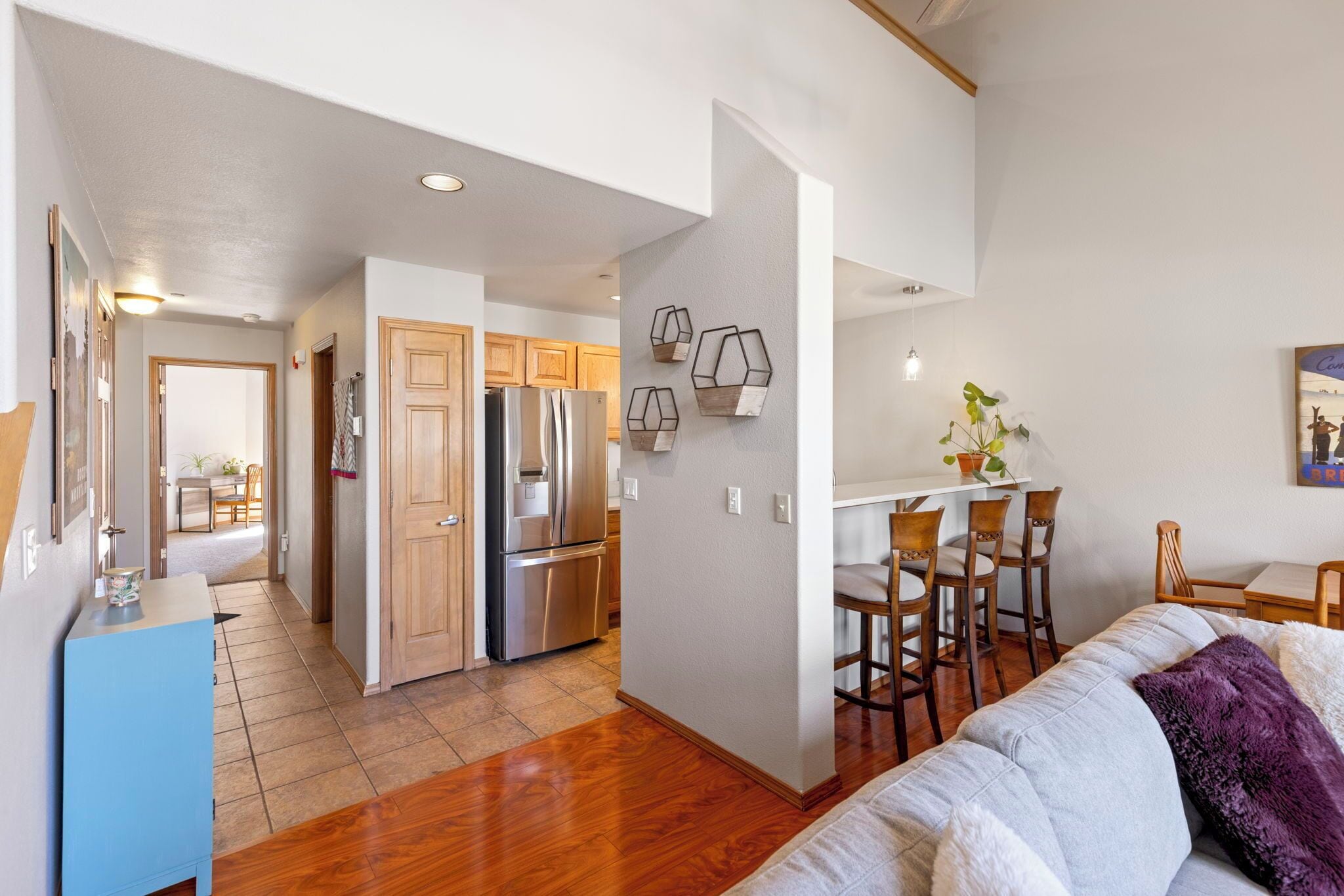 A modern kitchen with wooden cabinets, a stainless steel refrigerator, and a dining area with a white table and chairs.