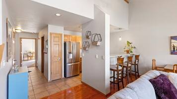 A modern kitchen with wooden cabinets, a stainless steel refrigerator, and a dining area with a white table and chairs.