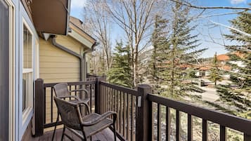 A wooden deck with a chair and a railing overlooking a residential area with trees and houses.