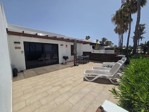 A covered outdoor area with a barbecue grill, lounge chairs, and a patio table. - 2 Bedroom Beachfront Playa Flamingo Apartment with Private Terrace & Air Con (Playa Blanca)