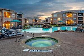 A swimming pool with lounge chairs, a hot tub, and a warning sign indicating no diving. - Landing Stunning 1bd, Gym (McKinney)