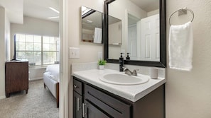 A bathroom with a white sink, dark cabinets, a large mirror, and a towel hanging on the wall. - Landing Stunning 1bd, Gym (McKinney)