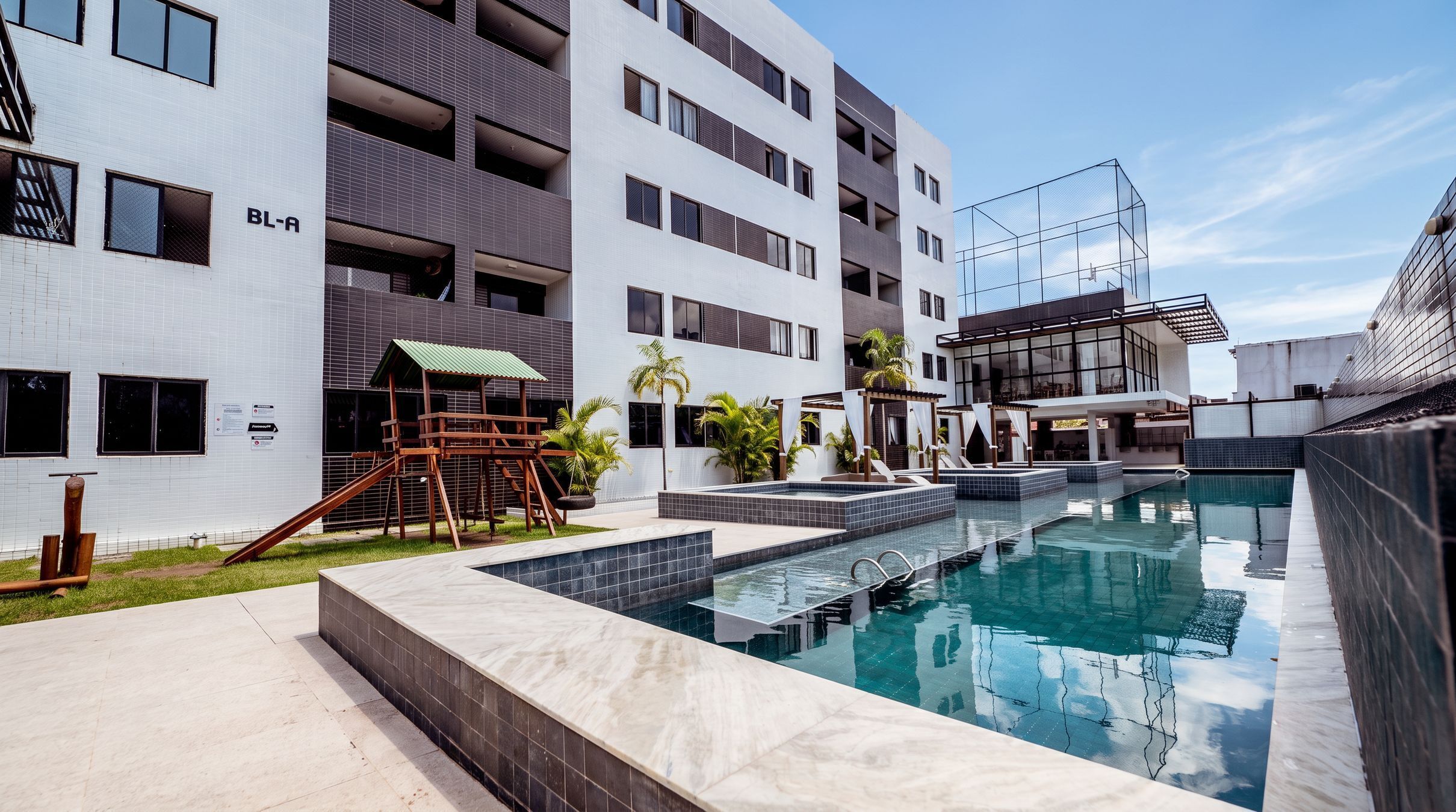 Um edifício moderno com piscina, área de estar ao ar livre e espaço de recreação infantil.