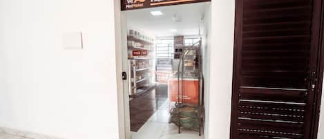 A MiniMarket entrance with a glass door, a metal staircase, and a tiled floor.