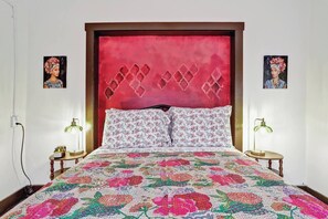 A bed with a floral bedspread, a red headboard, and two bedside lamps. - Posada Linda - 4 separate suites 2m to downtown! (Las Cruces)