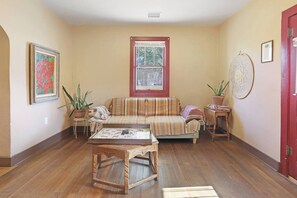 A living room with a sofa, a coffee table, and two potted plants.