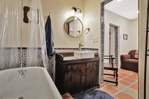 A bathroom with a bathtub, a sink, and a mirror. There is a towel hanging on the wall and a shower curtain.
