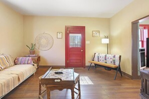 A living room with a sofa, a coffee table, a bench, a door, and a lamp. - Posada Linda - 4 separate suites 2m to downtown! (Las Cruces)