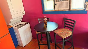 A compact kitchen with a washing machine, a small table, and two chairs.
