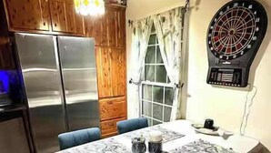 A dining area with a table set for two, a dartboard, and a refrigerator. - Tennessee River Cabin - Loft, Grill & Lake Access (Waverly)