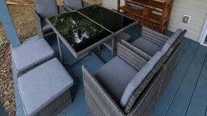 A covered outdoor seating area with a table and chairs, a ceiling fan, and a view of a house. - Tennessee River Cabin - Loft, Grill & Lake Access (Waverly)