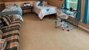 A bedroom with a sloped ceiling, a bed, a desk, and a chair. - Tennessee River Cabin - Loft, Grill & Lake Access (Waverly)