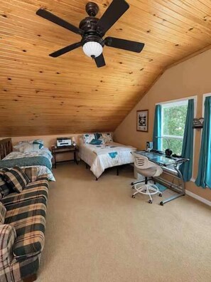 A bedroom with a sloped ceiling, a bed, a desk, and a chair.